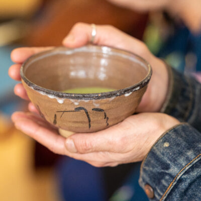 Hand holding a tea bowl with matcha in.