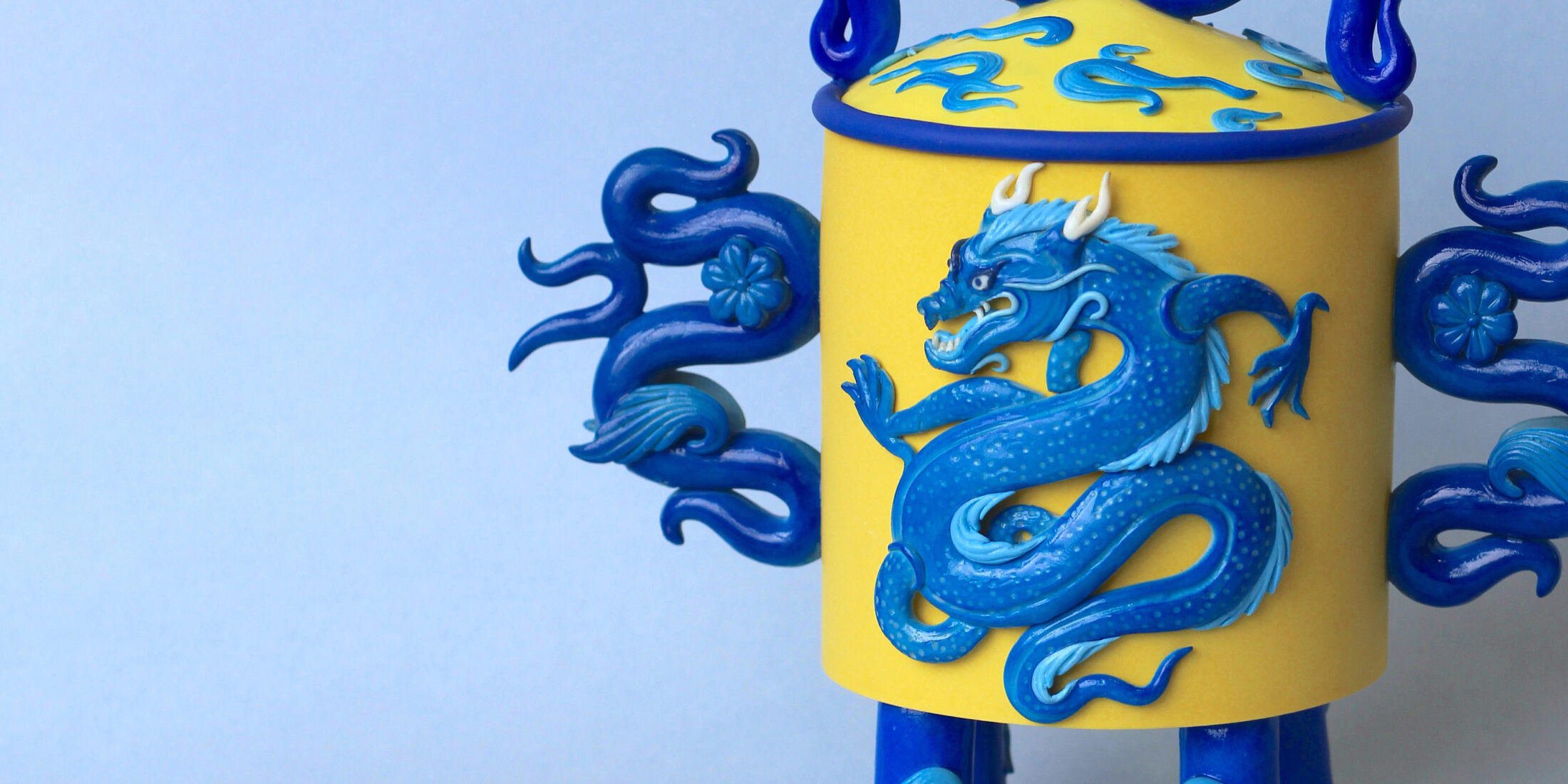 Yellow and Blue clay vessel with a blue dragon featured on the front.